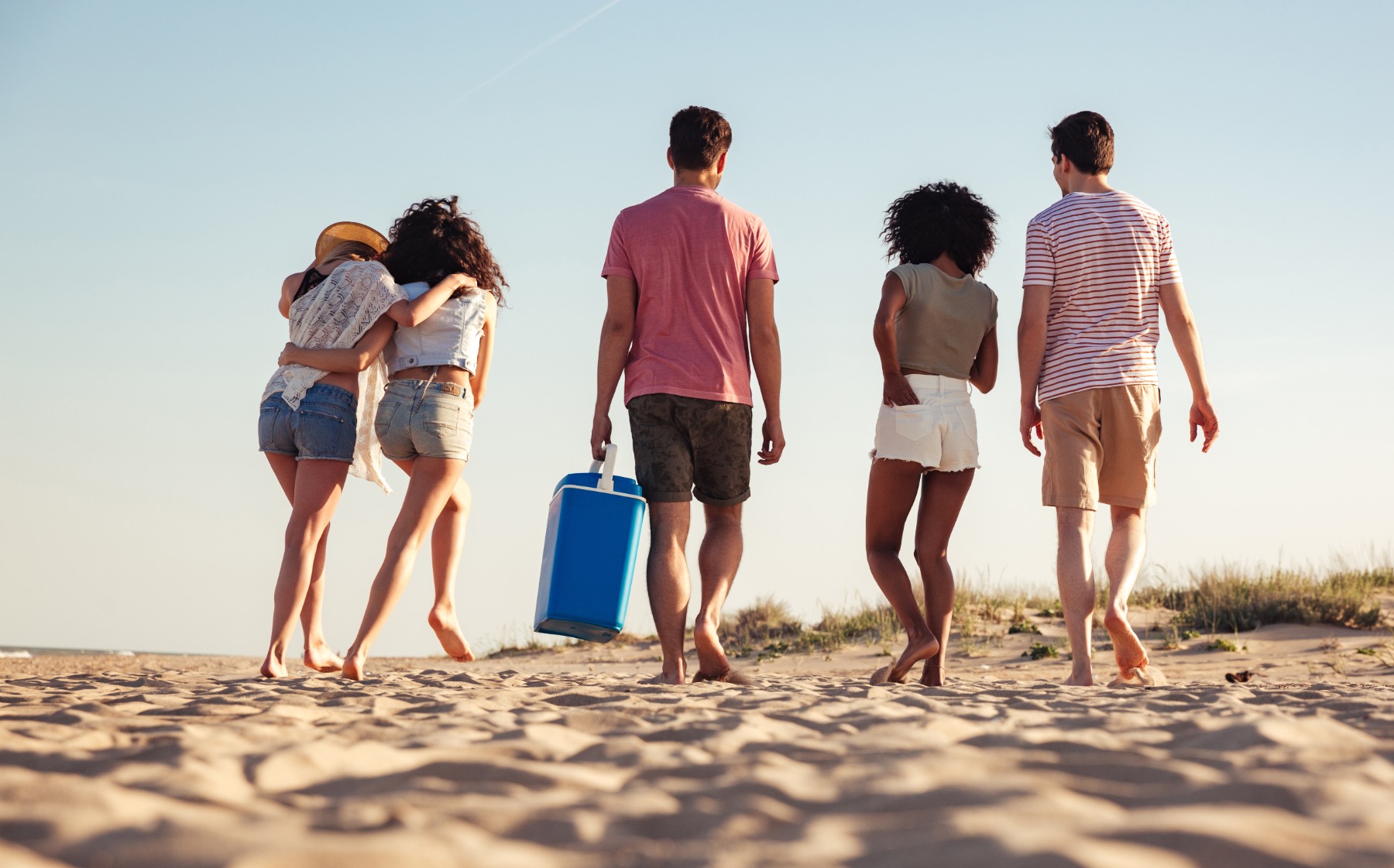 5 young people walking on a beach