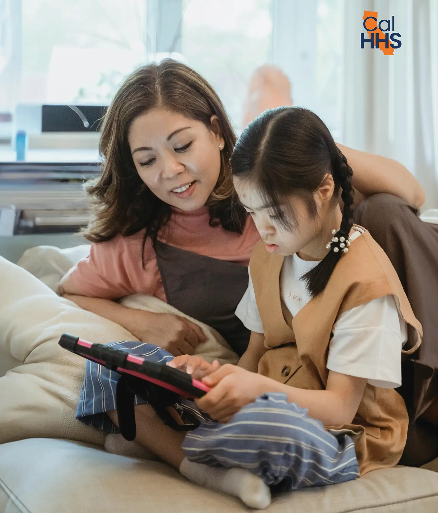 photo of girl holding an ipad with adult woman supervising her